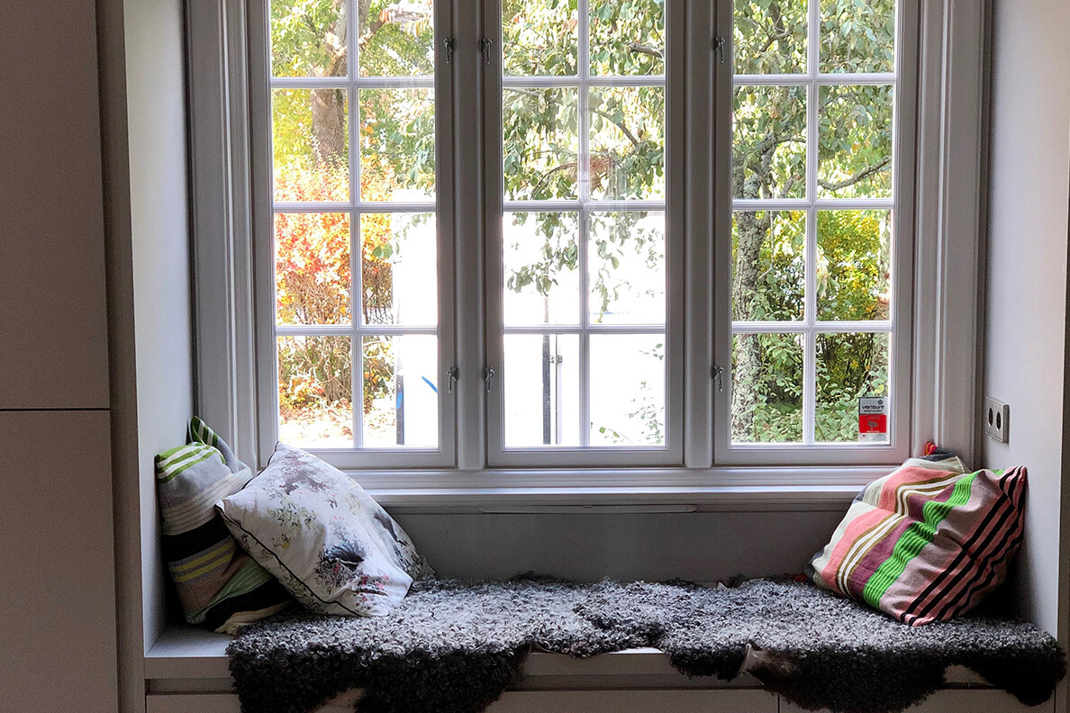 Platsbyggd soffa i fönster och färglada kuddar