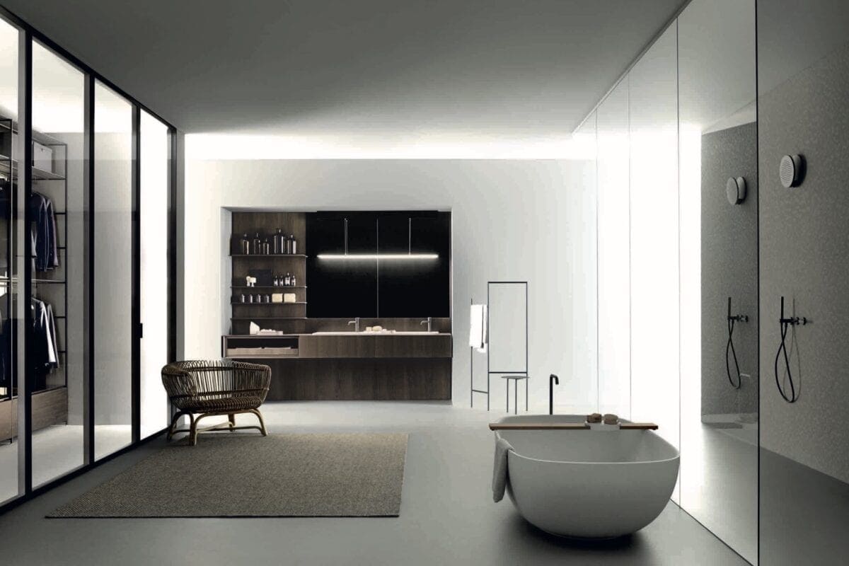 Stort lyxigt badrum med ovalt badkar, en korgstol i hörnan och väggar i glas.