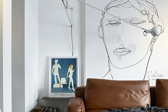 Ljust och fräscht vardagsrum med ljusbrun skinnsoffa, konst på väggarna och randig matta.