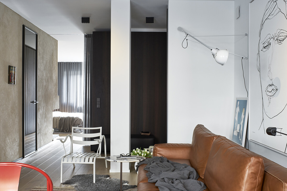 Modernt vardagsrum med ljusbrun skinnsoffa, grå filt, konst och lampor på väggarna